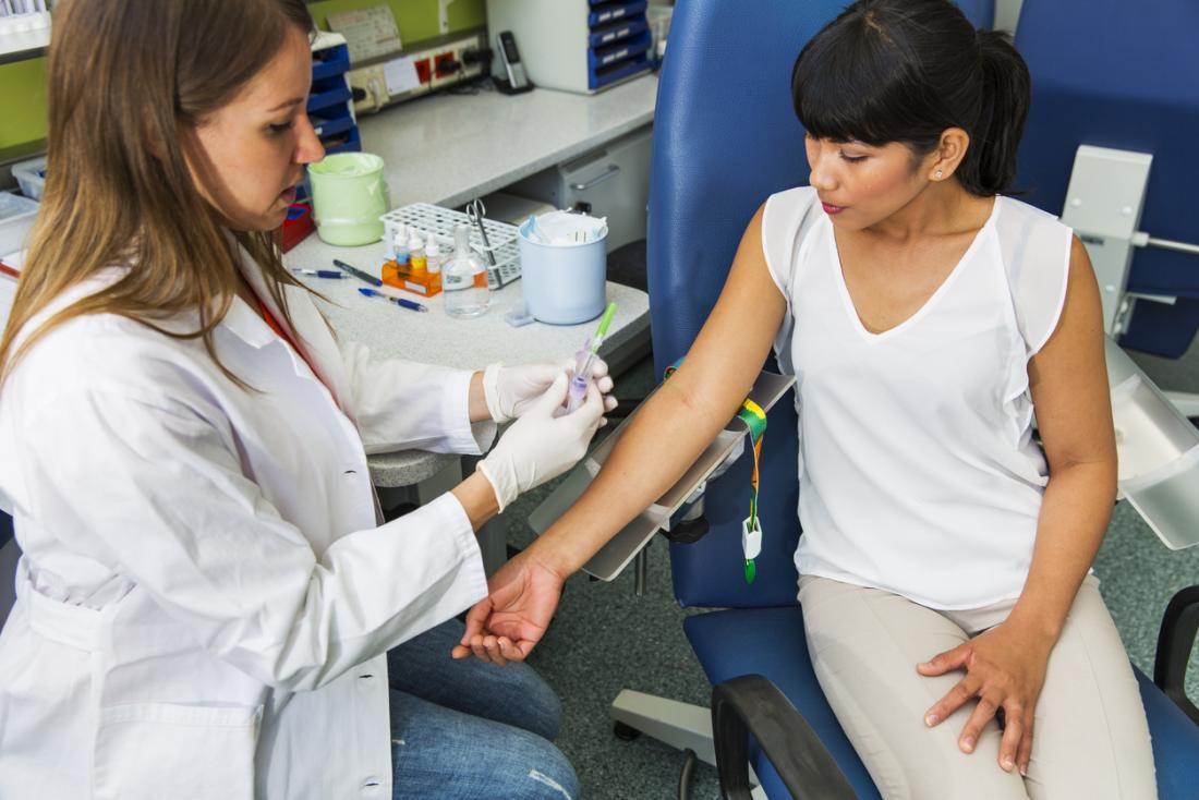 Femme se préparant à faire un don de plasma sanguin avec un technicien.