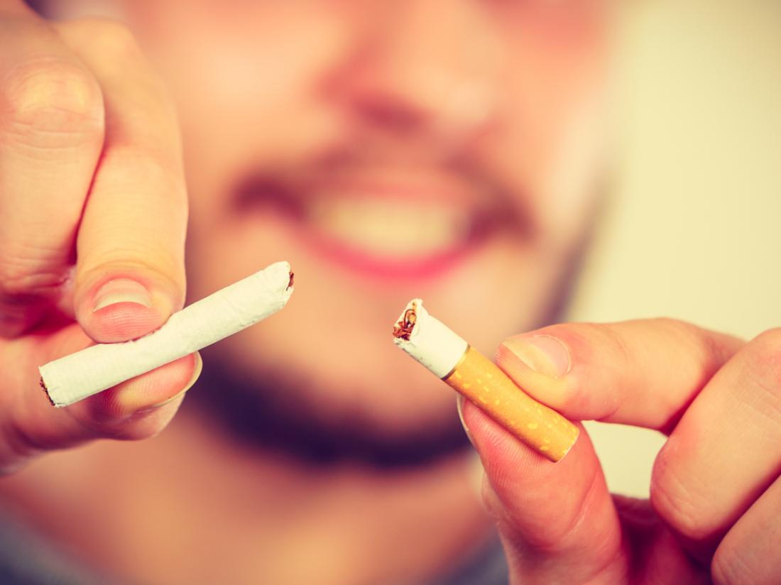 Mann bricht Zigarette in zwei Hälften