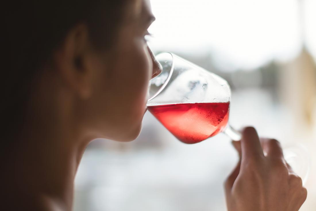 Frau, die rosafarbenen Wein trinkt, der mit den weichen Schemeln verbunden sein kann