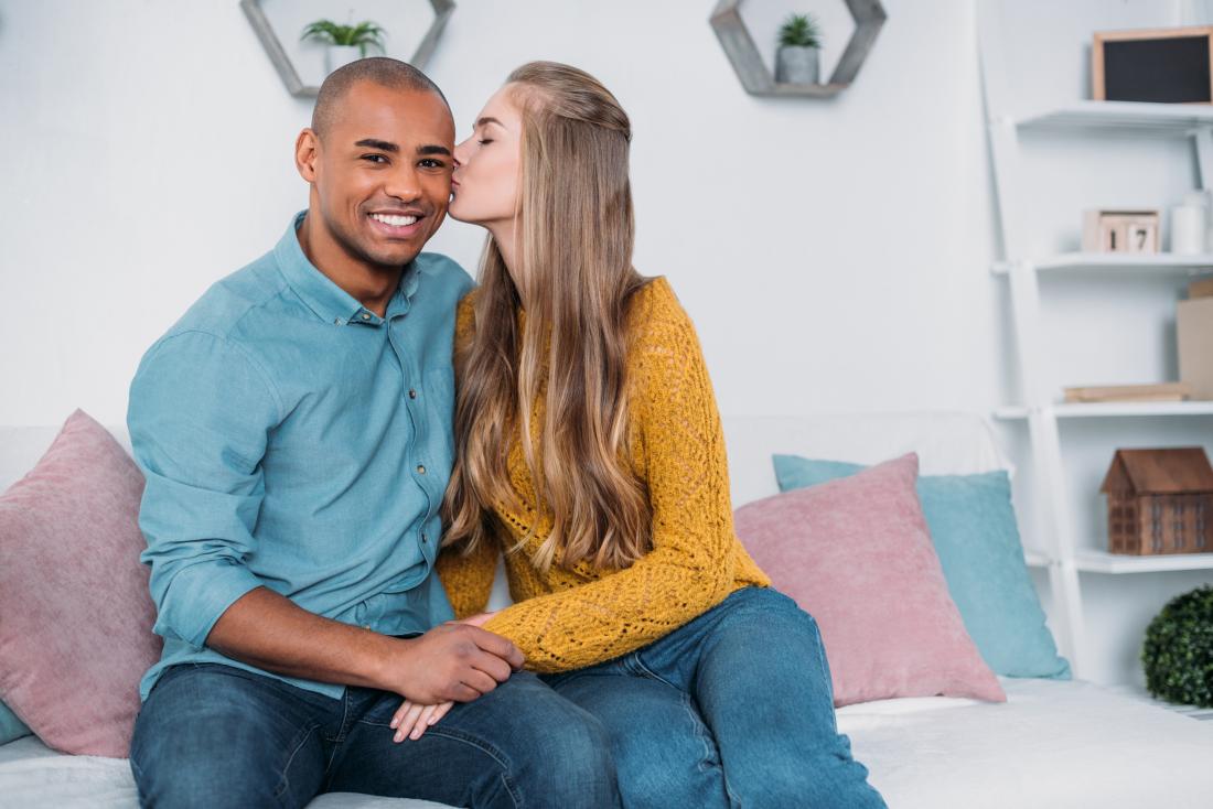 Paar auf der Couch küssen, die virale Meningitis verbreiten kann