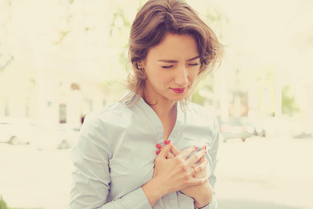 Жена, която държи гърдите си с евентуален сърдечен удар