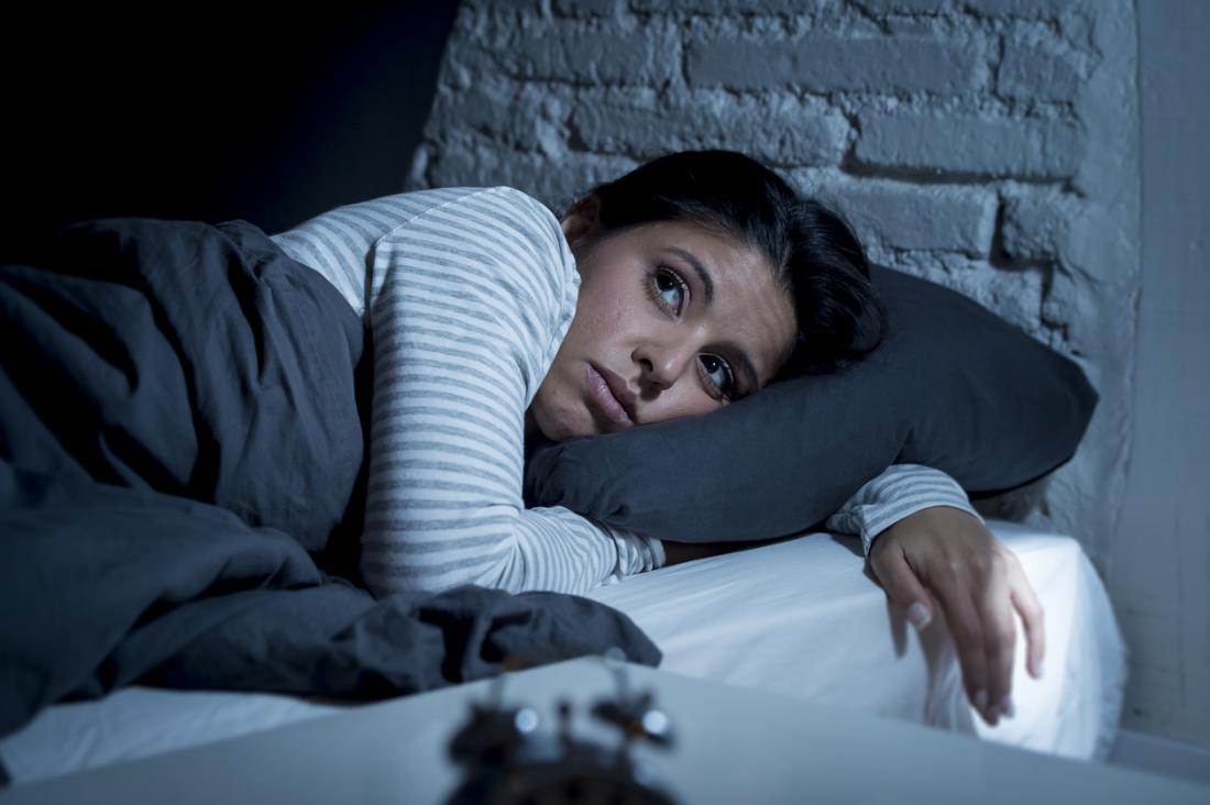 une femme au lit incapable de dormir probablement en raison d'une crise cardiaque venant en sens inverse