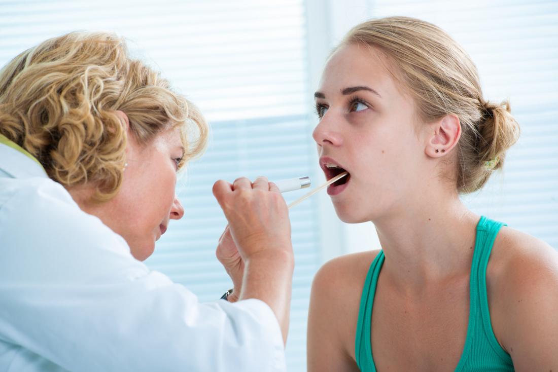 Docteur examinant la langue et la gorge.