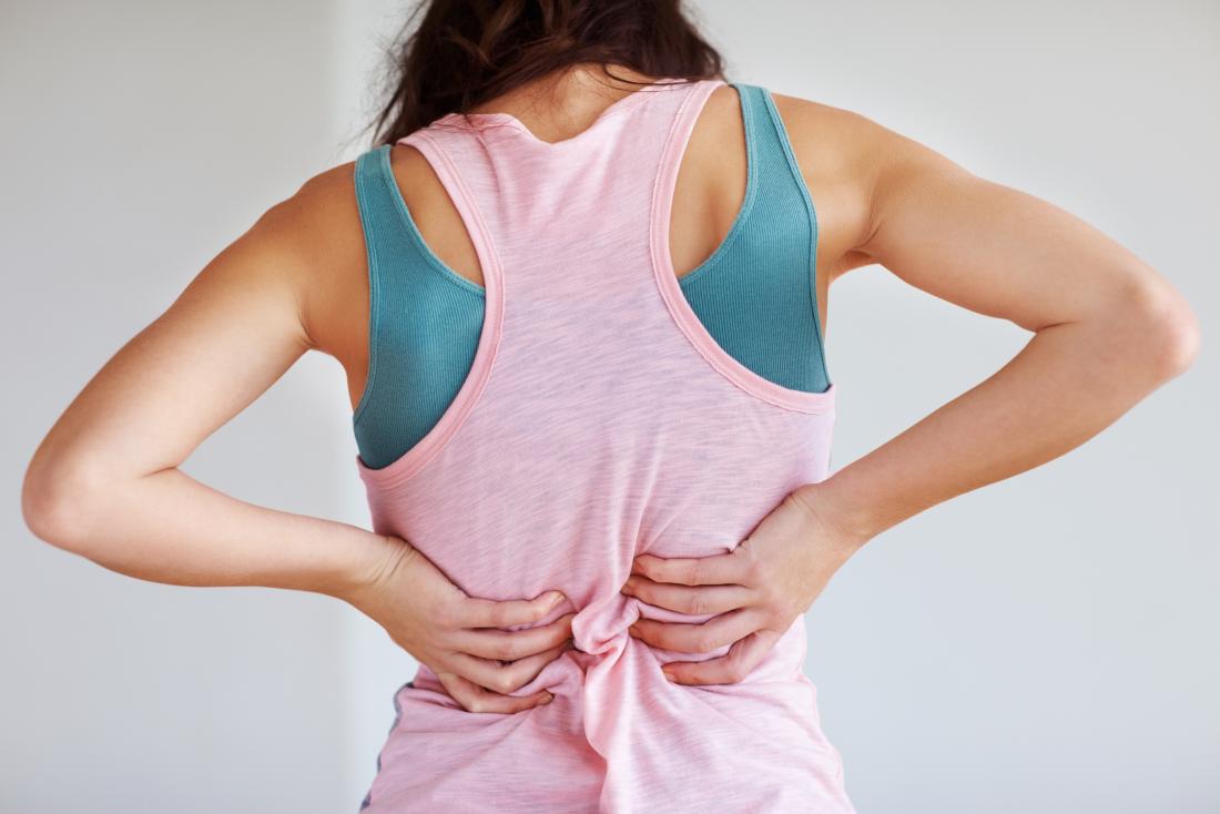 La donna in esercizio e gli sport indossano con rigidità muscolare nella parte posteriore.