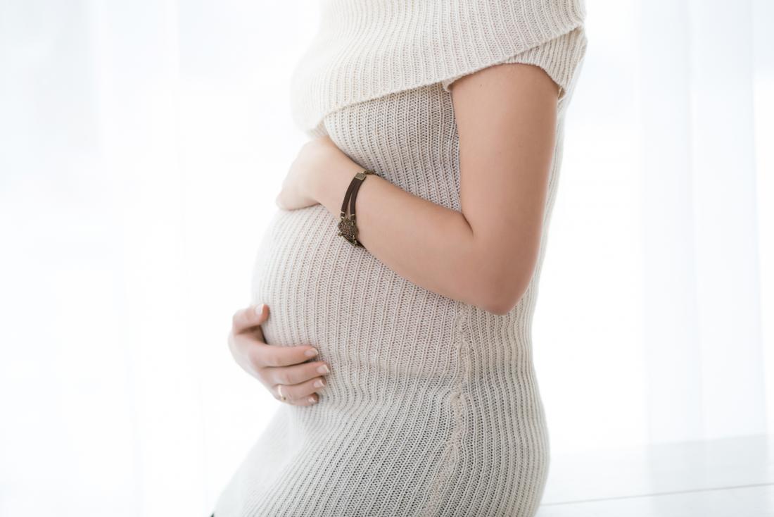 schwangere Frau hält ihren Bauch mit Schmerzen unter der linken Brust