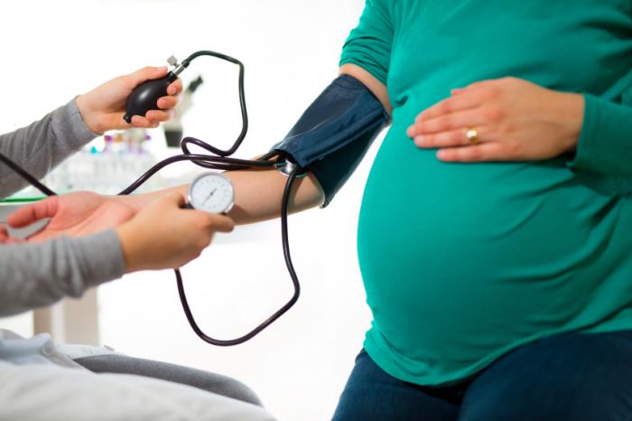 Una donna incinta sta misurando la sua pressione sanguigna.