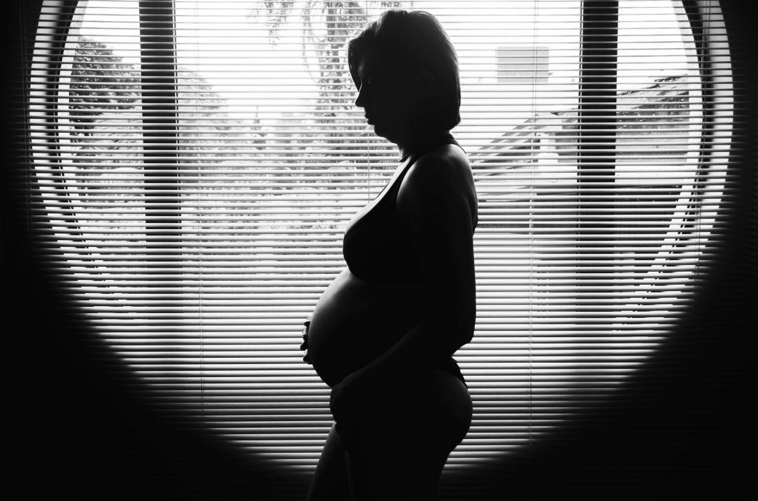 femme enceinte réfléchie dans la fenêtre basse niveaux hcg