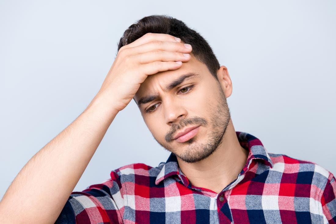 Homme avec maux de tête au sommet de la tête, tenant le front dans la douleur.