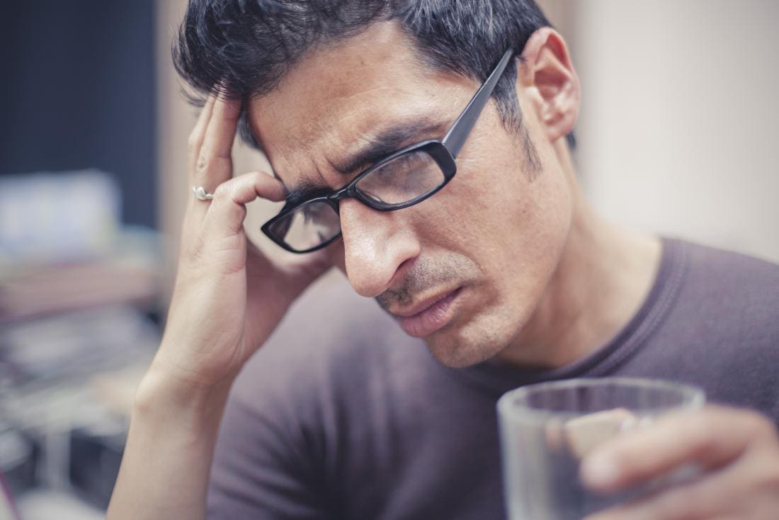 Homme avec maux de tête sur le côté droit de la tête tenant la tête et tenant le verre.