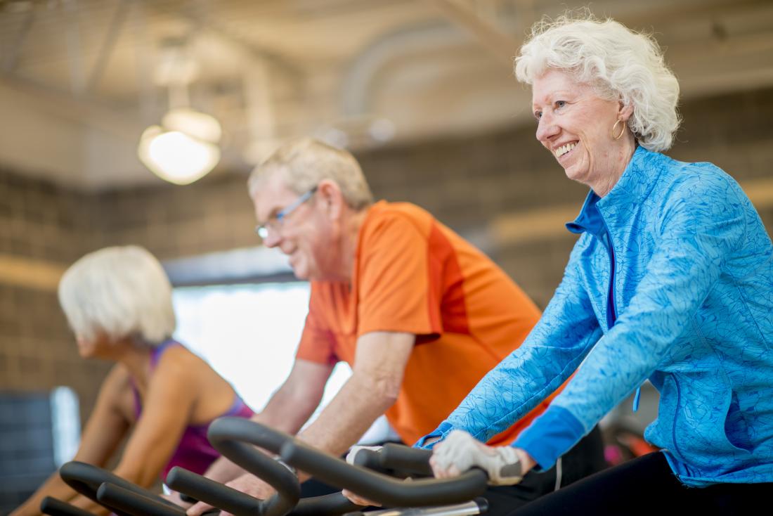 Classe de sêniores no gym nas bicicletas de exercício que dão um ciclo.