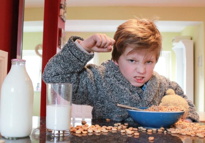 Ein Kind macht ein Durcheinander seiner Frühstücksflocken.
