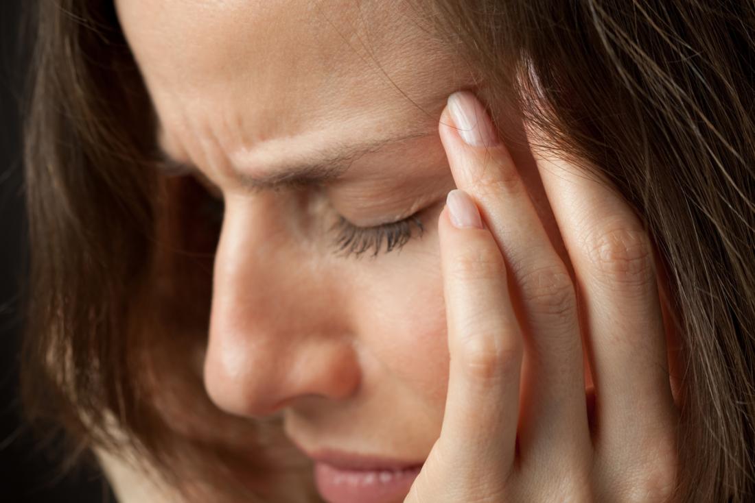 Femme tenant le côté de son temple dans la douleur à cause d'une migraine basilaire.