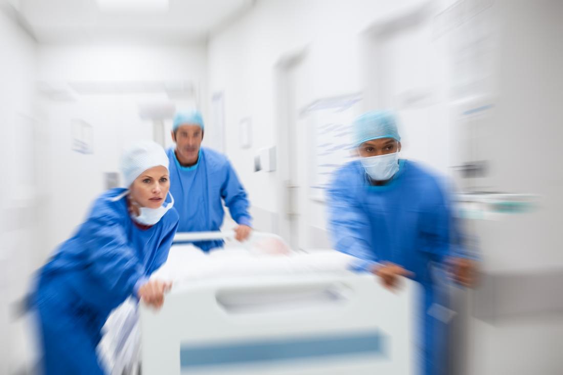 Ärzte hetzen einen Patienten in einem Bett durch ein Krankenhaus. Mögliche strangulierte Hernie