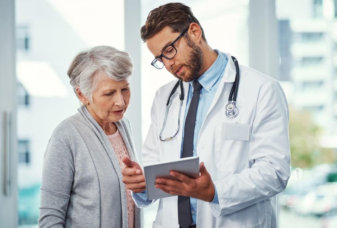 Jeune homme médecin parlant avec une patiente mature.