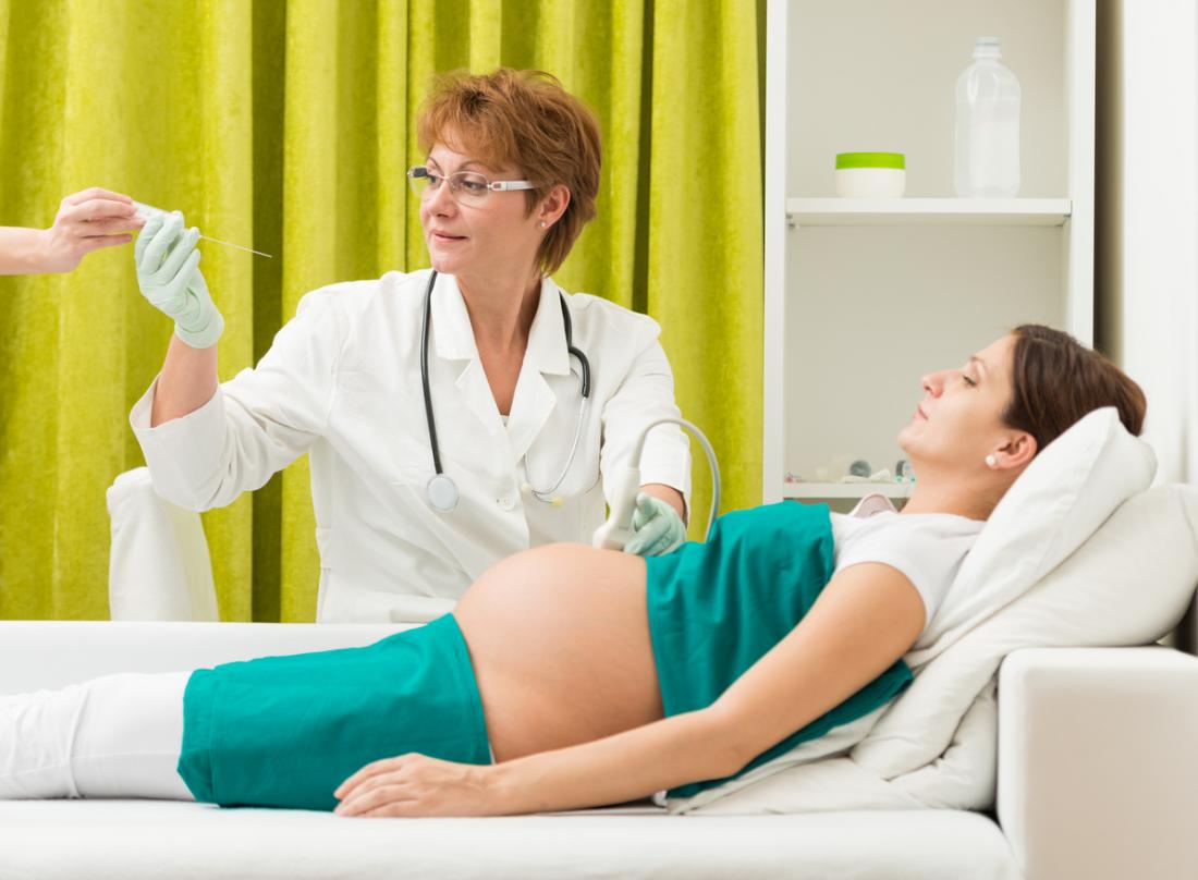 Donna incinta che ha liquido amniotico disegnato per analisi durante un'ecografia.