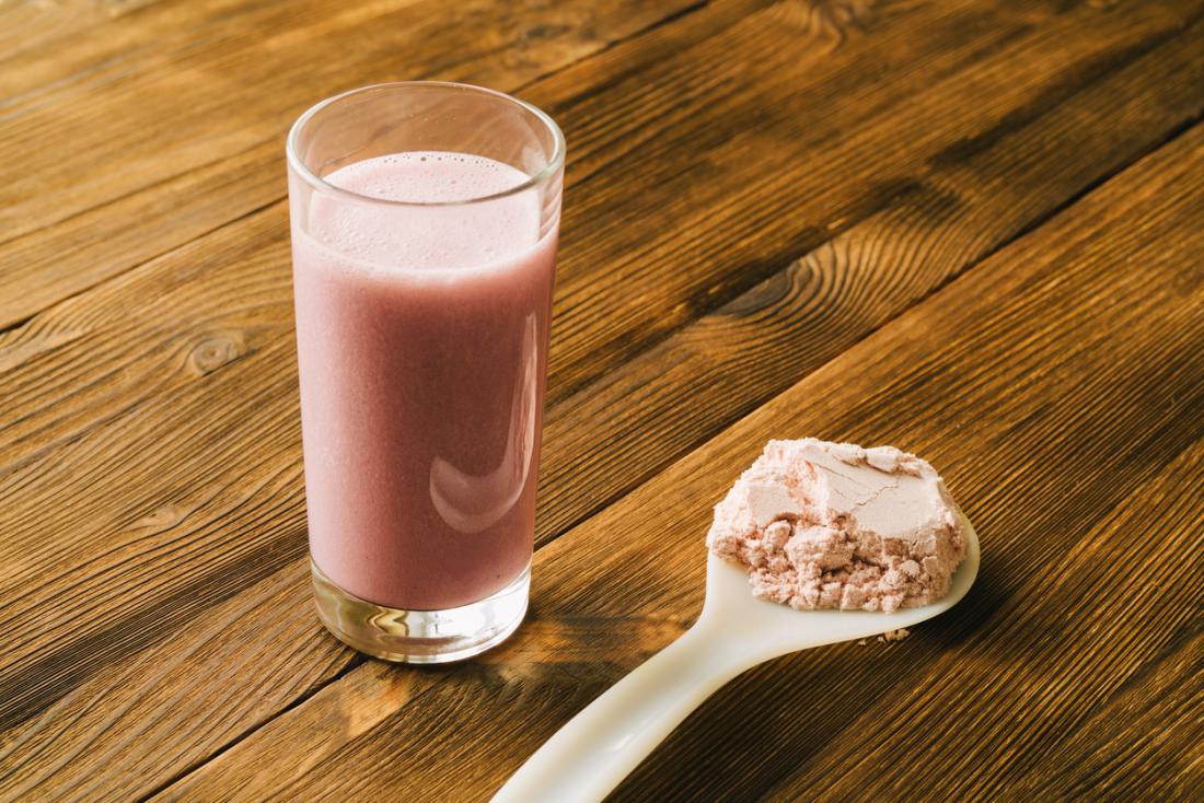 shake di proteine ​​in polvere su un cucchiaio e fatto in un bicchiere