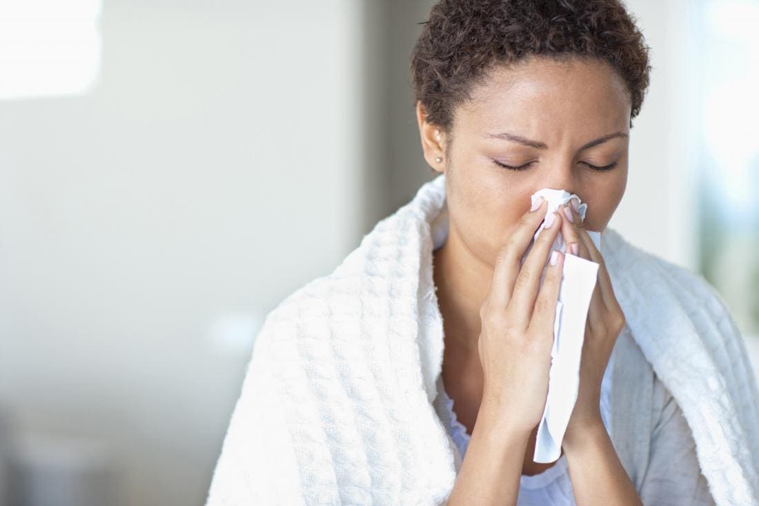 Donna che starnutisce e soffia il naso nel tessuto a causa della congestione nasale.