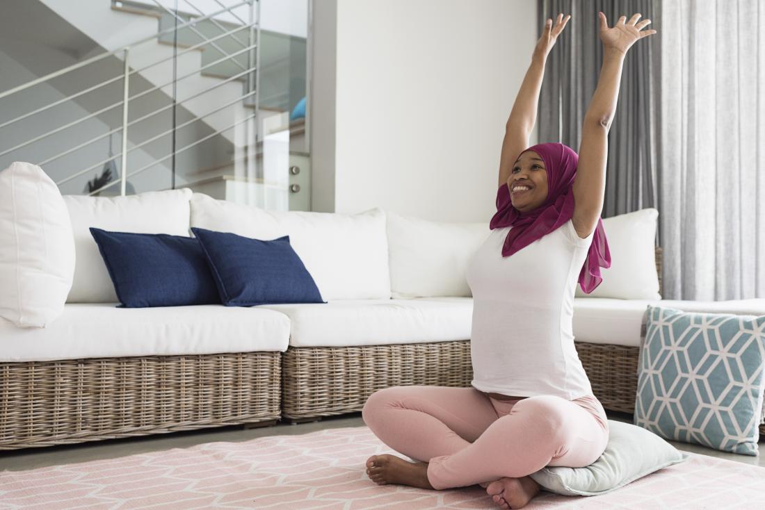 Жена, изпълняваща йога, се простира у дома, за да подобри болката в гърба