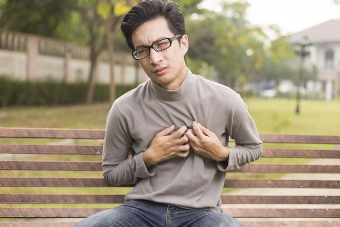 公園のベンチに座っている胸の痛みを持つ若い男