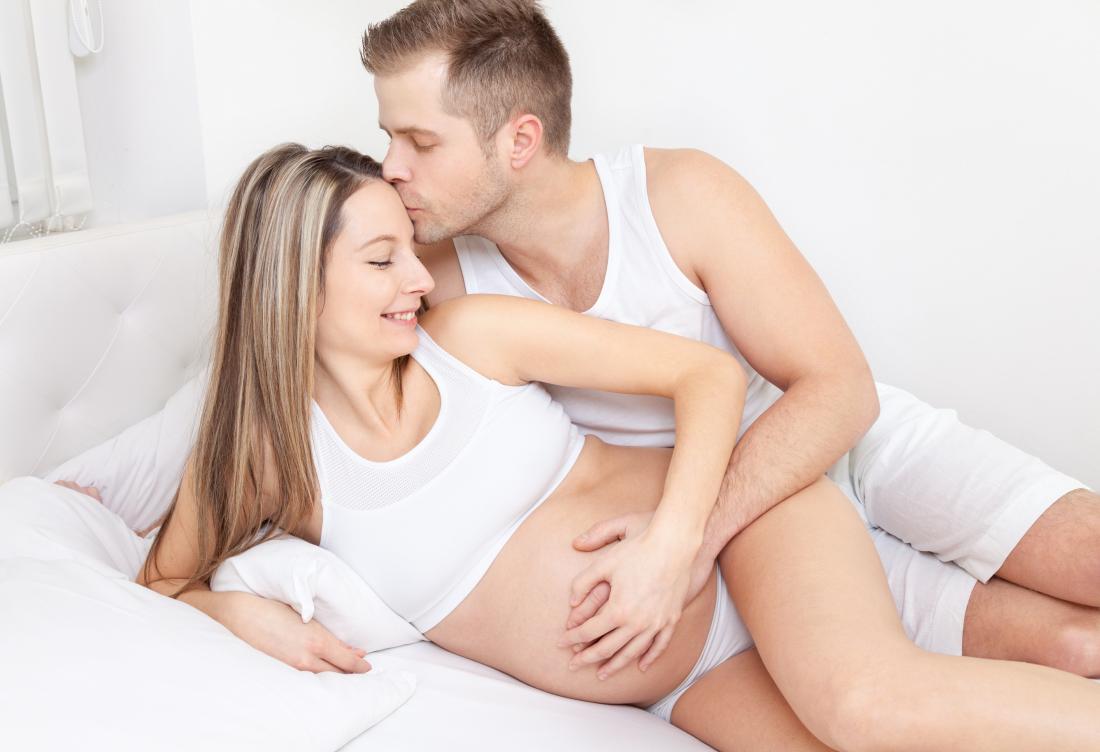 Donna incinta a letto con il partner che considera il sesso durante la gravidanza