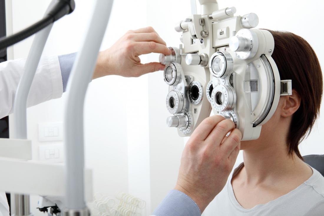 眼科医に眼科検査を受けている女性。