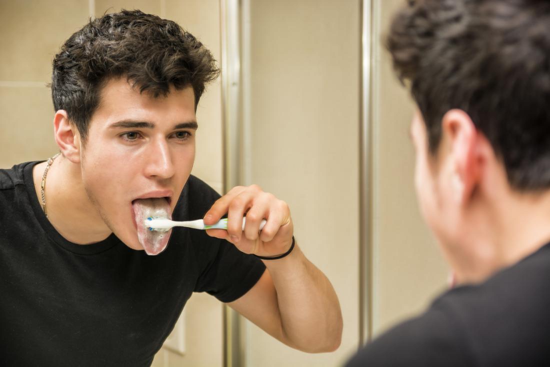 Giovane uomo si lavava la lingua nello specchio del bagno