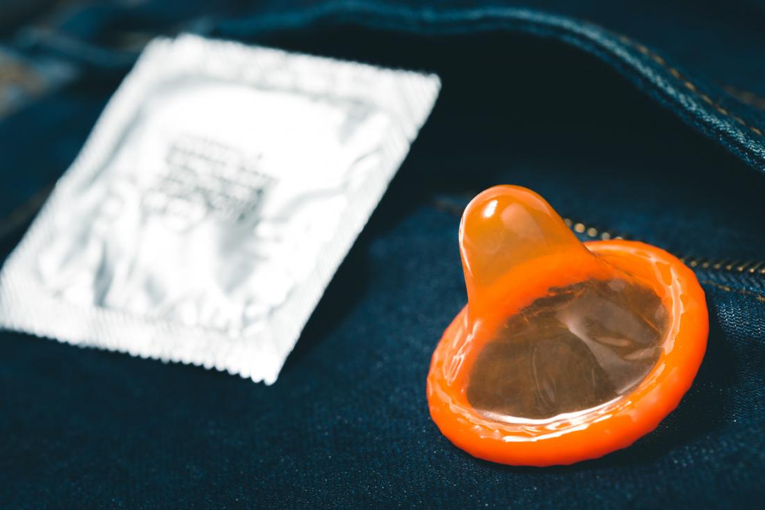 Оранжев презерватив на парче дънки до обвивката
