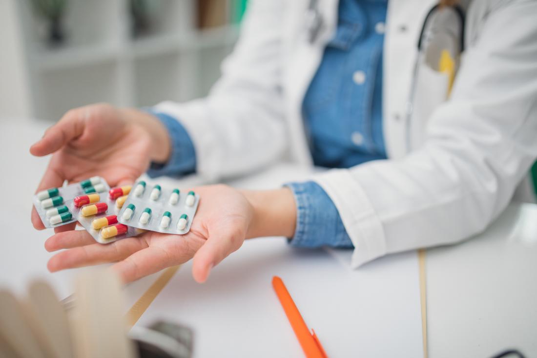 Medico con più pacchetti di pillole, farmaci e farmaci nelle mani offerte al paziente.