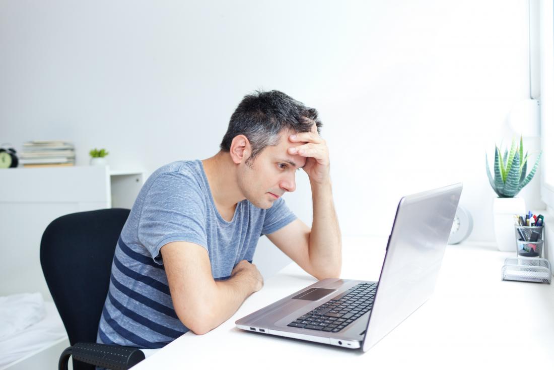 Натискан човек, който работи върху лаптоп с бяла и сива коса