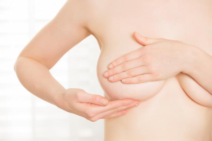 жена проверява гърдите за признаци на рак на гърдата