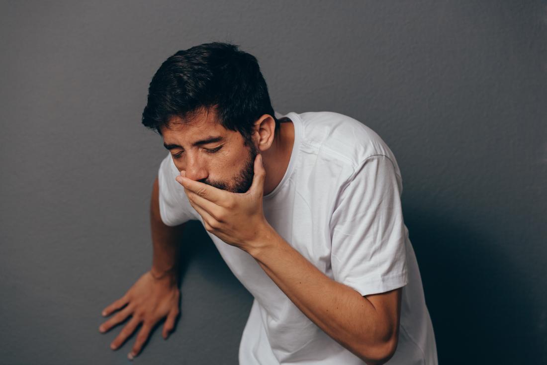 Homme sur le point de vomir de la bile verte ou jaune couvrant sa bouche avec sa main.