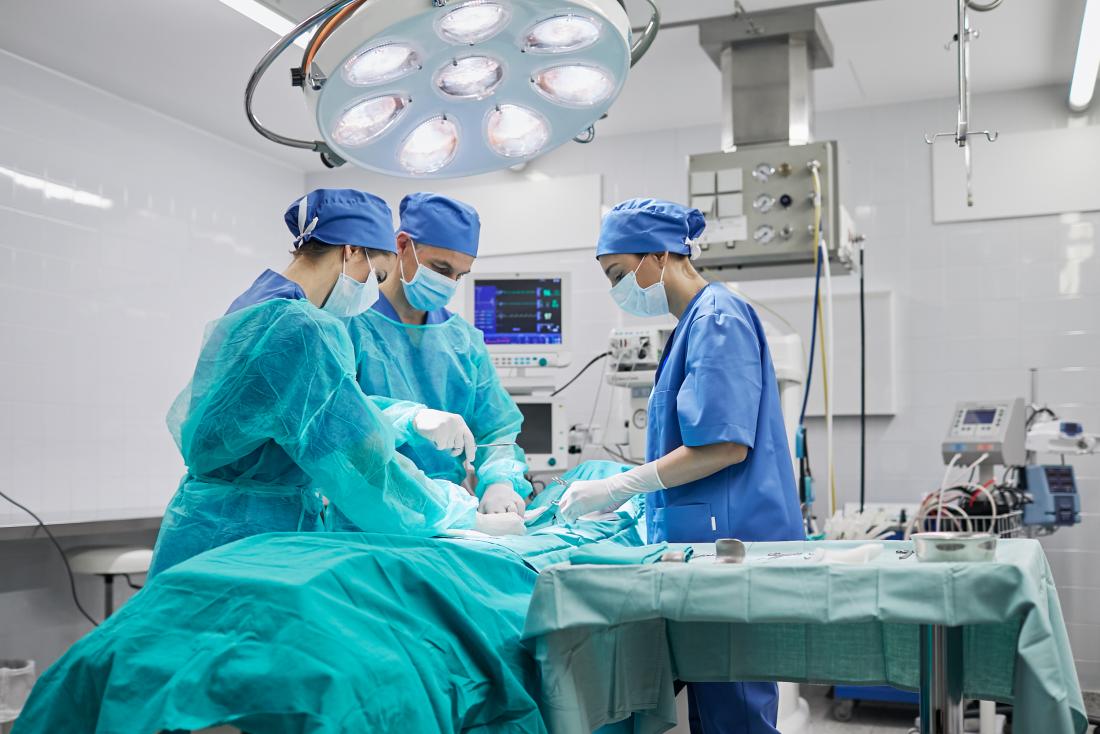 Хирурзите около операционната маса в ярко осветения театър.