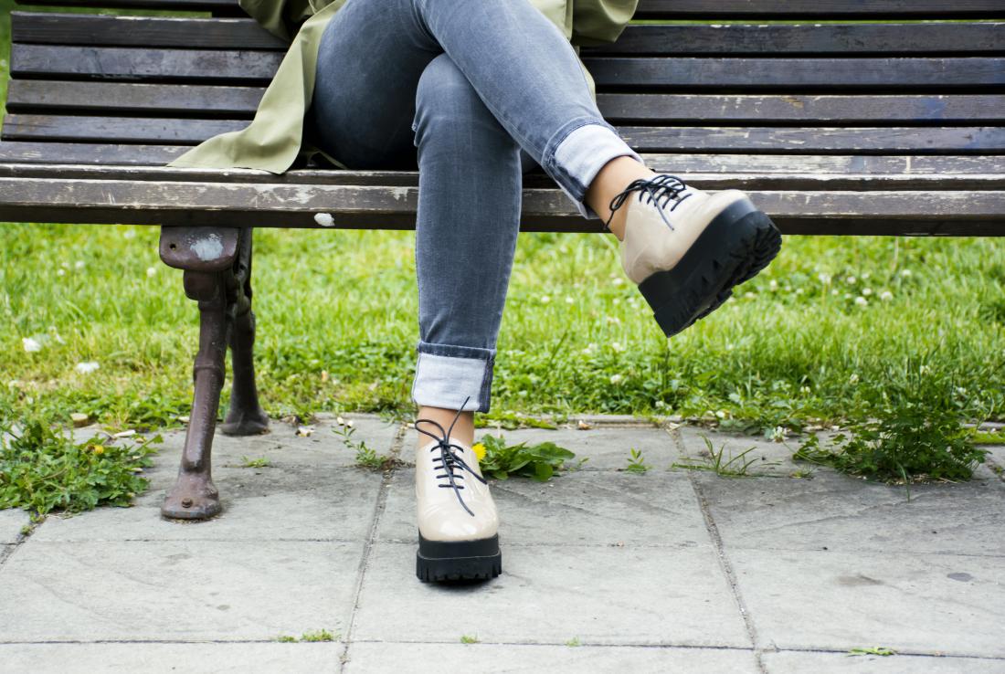 La donna si è seduta su una panchina con le gambe incrociate che possono causare intorpidimento alle gambe e ai piedi