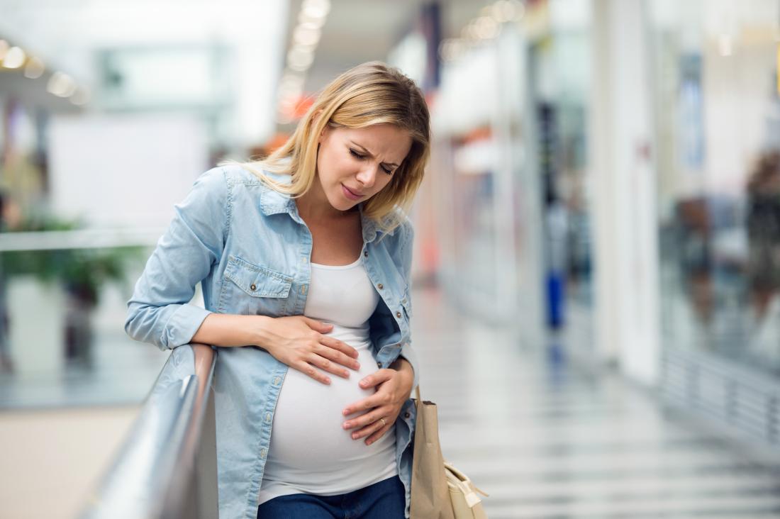 Donna incinta che tiene il suo stomaco con possibili spasmi di stomaco