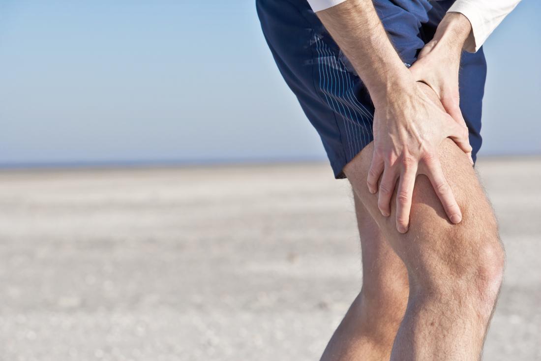 Personne à l'extérieur tenant la cuisse supérieure dans la douleur.