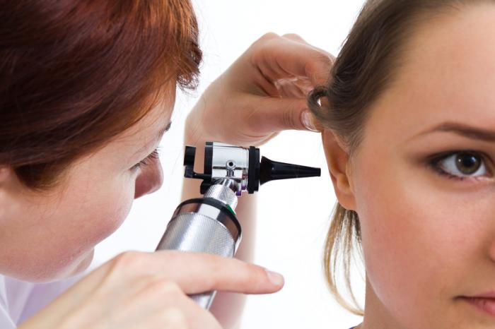 Un medico esamina un orecchio destro da donna con un otoscopio