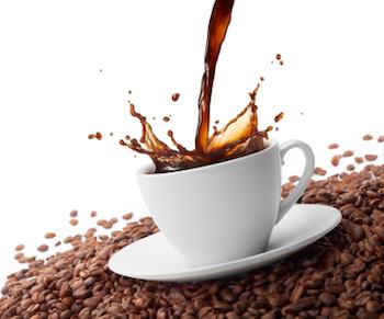 Kaffee wird in eine Tasse gegossen, die auf einem Bett aus Kaffeebohnen sitzt