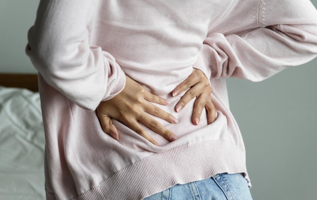 腰痛を持つ女性の背中の痛みと鼓腸