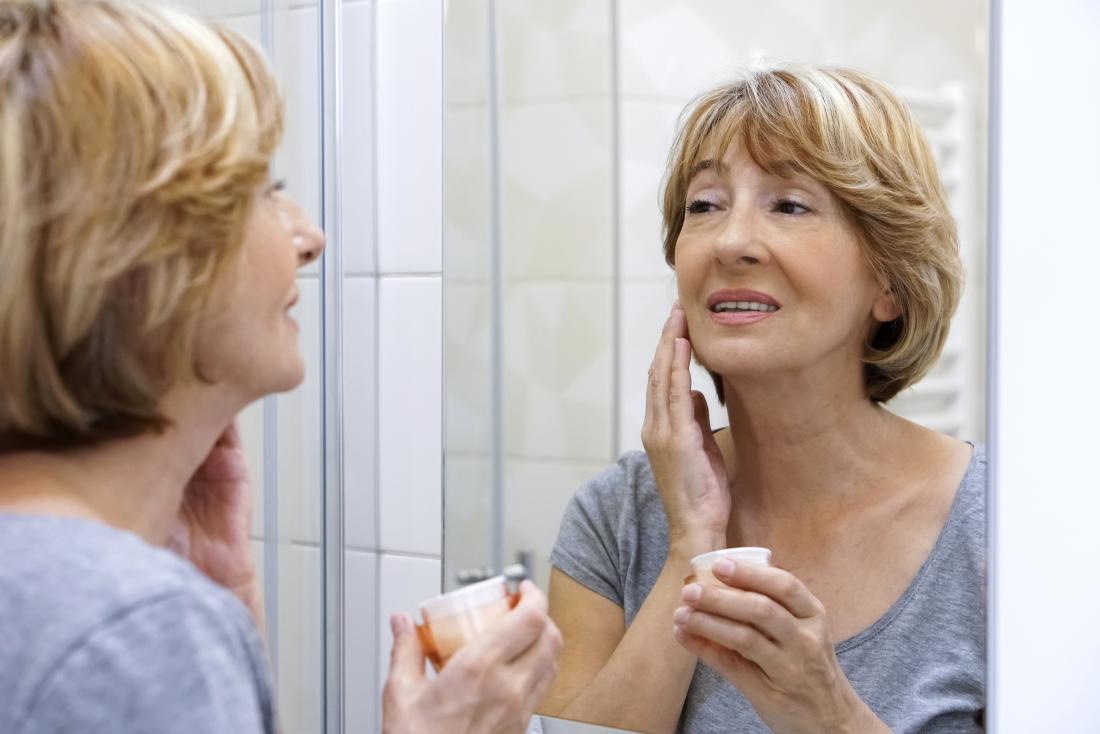 donna che usa la crema idratante sul viso per aiutare con l'eruzione della menopausa