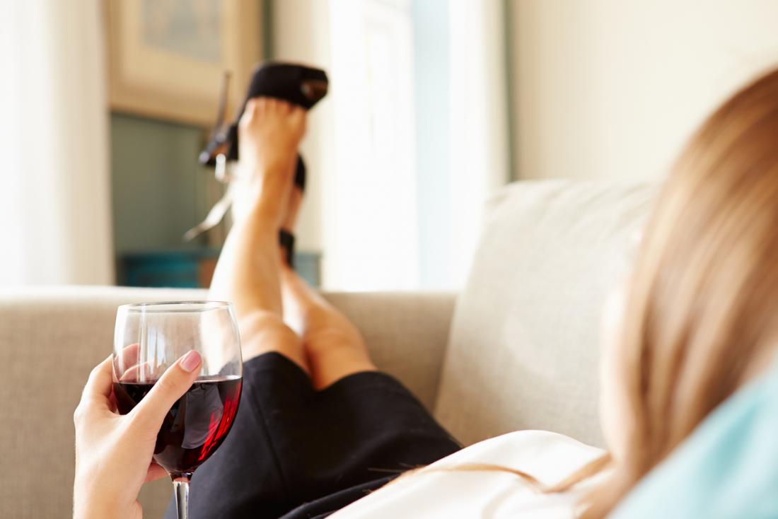 una donna sdraiata sul divano con un bicchiere di vino