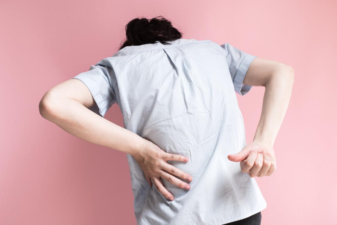 persona con dolore alla schiena su sfondo rosa