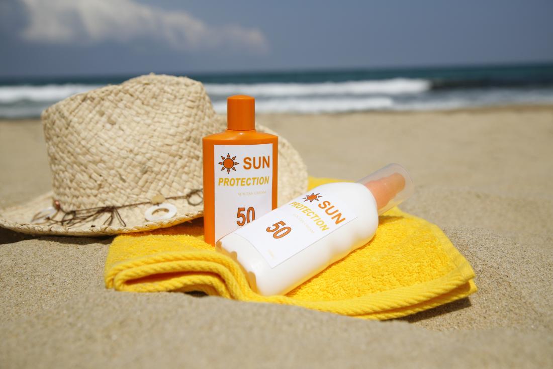 bottiglie di sole asciugamano lozione asciugamano e cappellino sulla sabbia